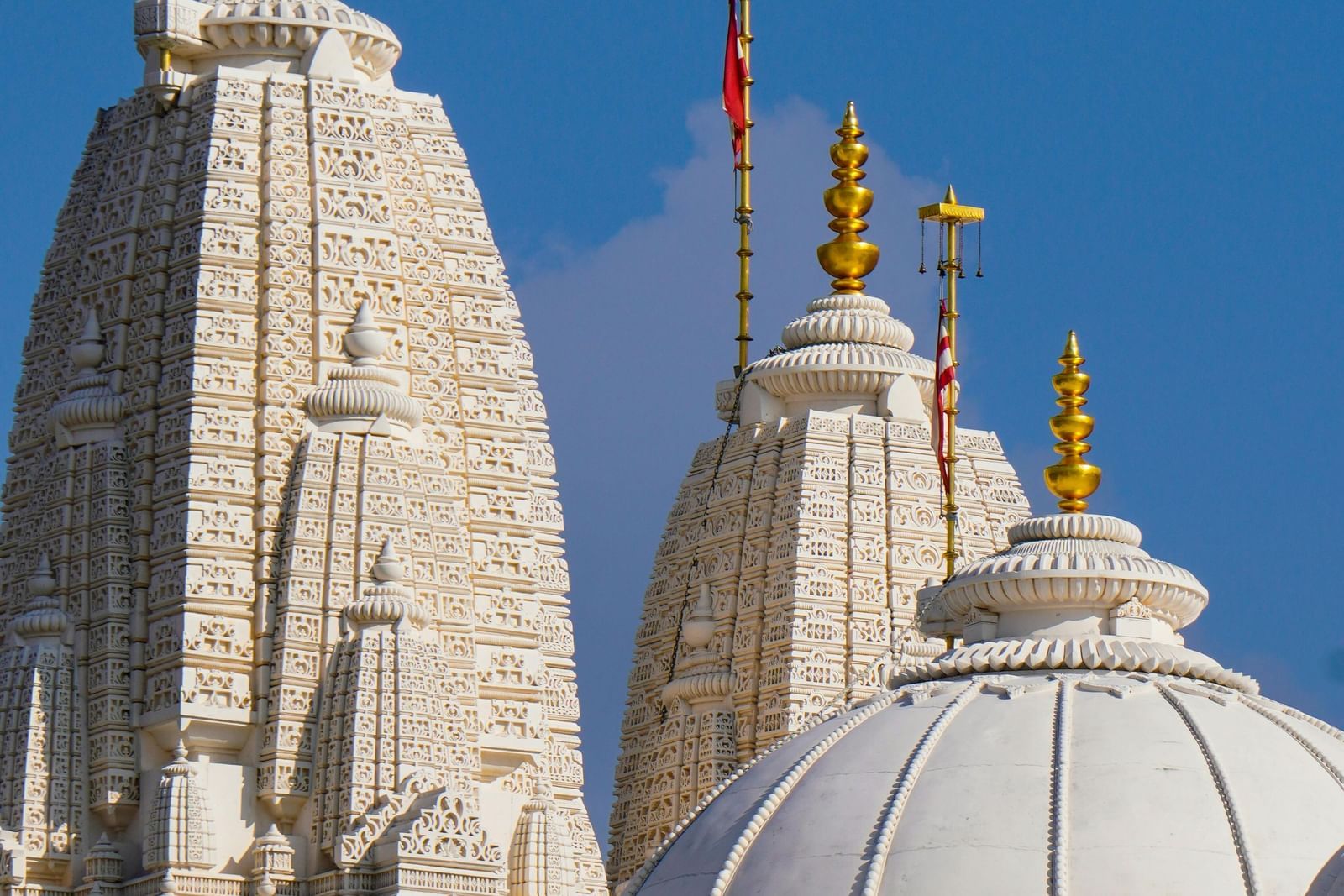 Multiple gopurams of a temple, seen with a bright sky in the backdrop.