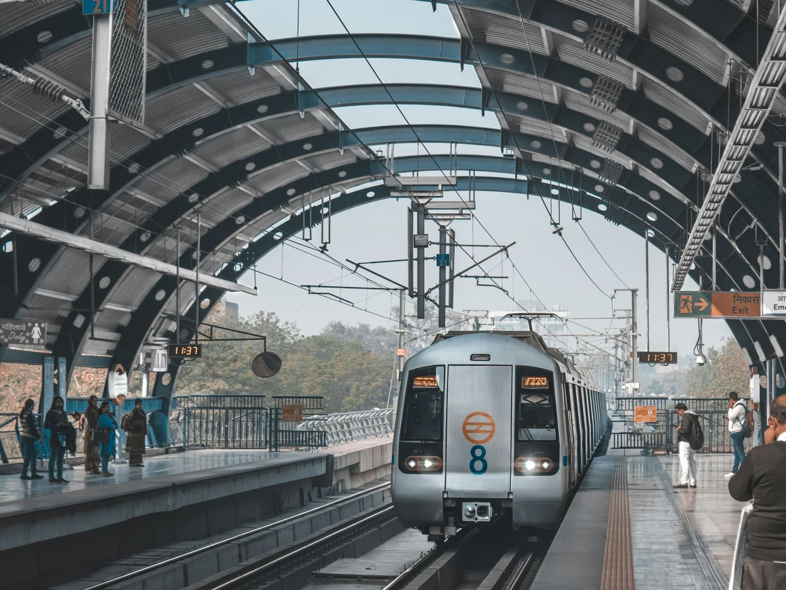  A metro train arriving at a station with an arched roof and tracks