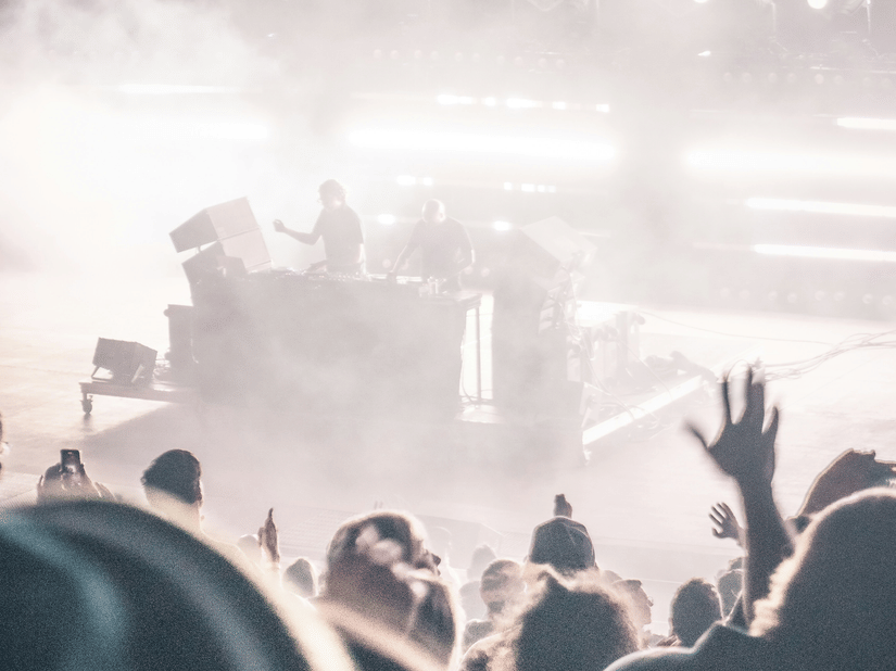 A view from the seats of a performer on the stage with smoke in the air during a concert.