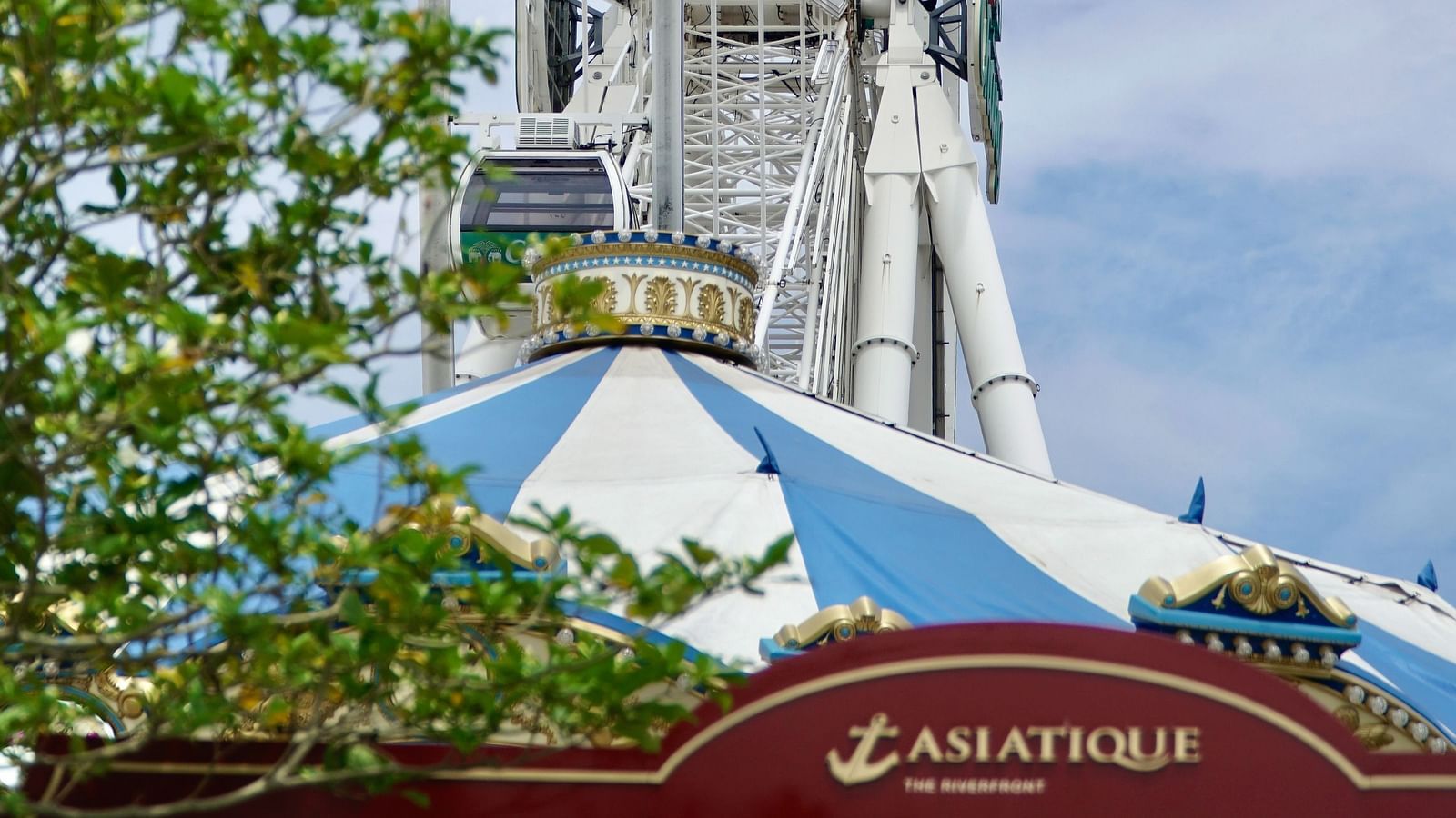 a ferris wheel above Asiatique the Riverfront restaurant's signage