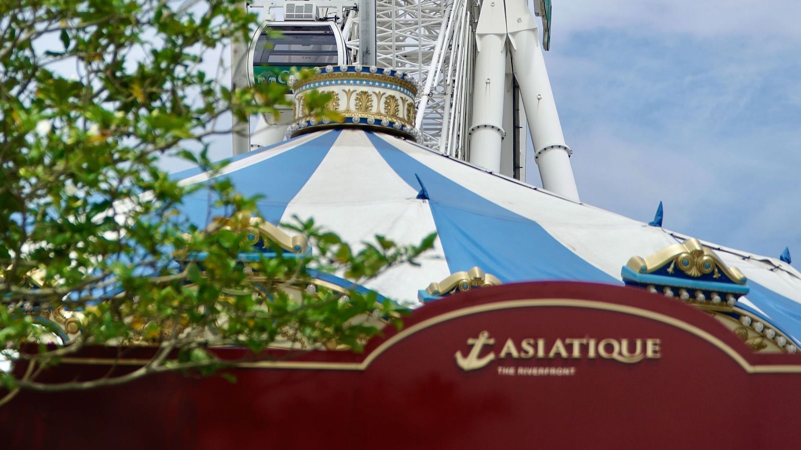 a ferris wheel above Asiatique the Riverfront restaurant's signage