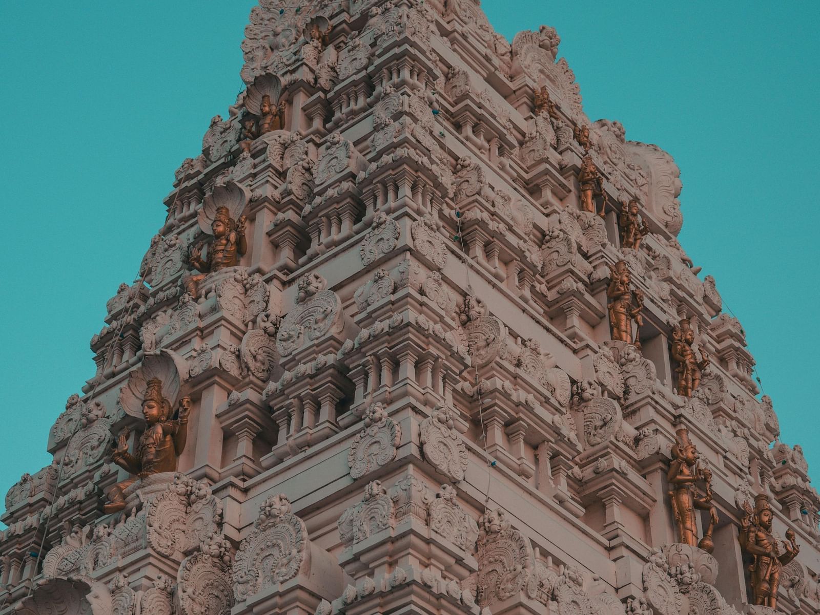 A towering temple gopuram with intricate carvings against a vibrant sky.