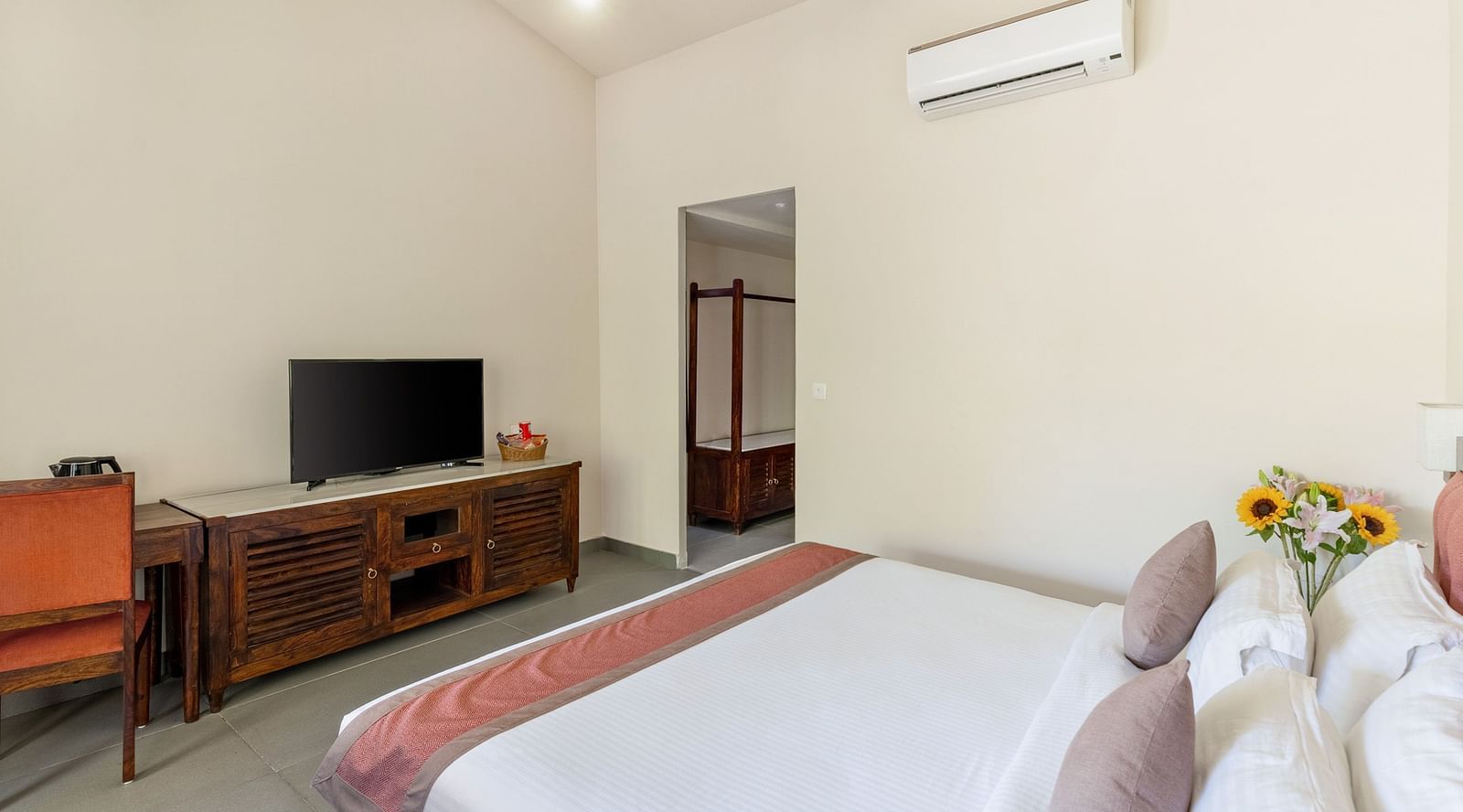 corner view of the luxury cottage room at aranya vilas featuring a king size bed along with a tv table with a television kept over it