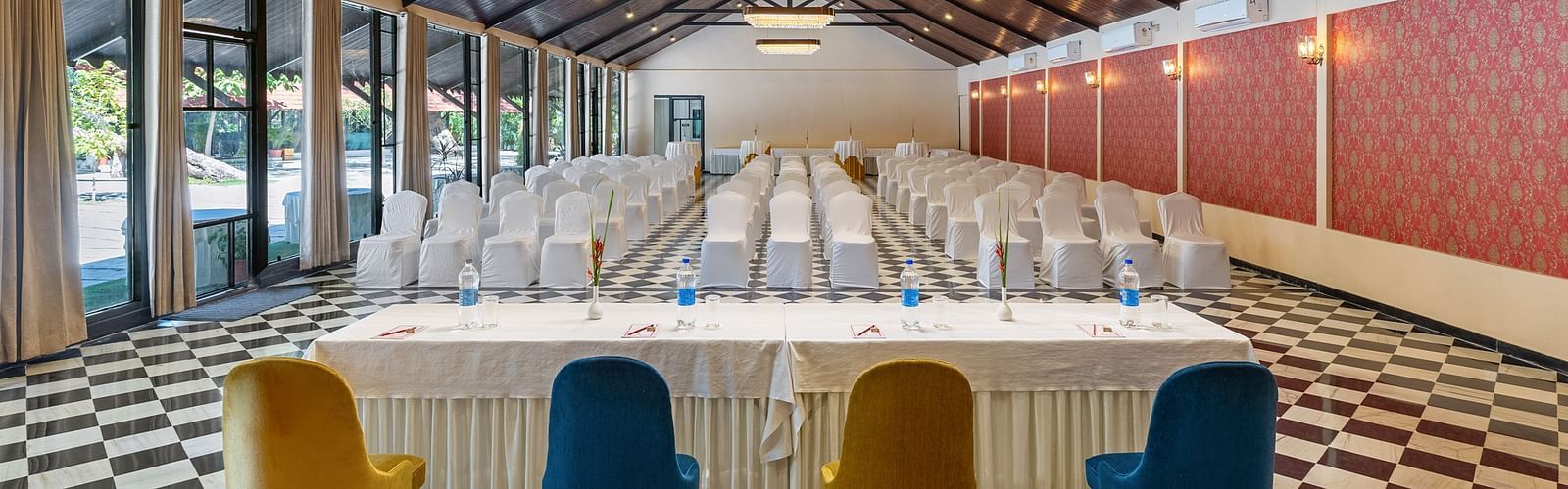 image of the banquet hall streching tot he very end of the room featuring lush green atmosphere from the window  panels in the left at aranya vilas