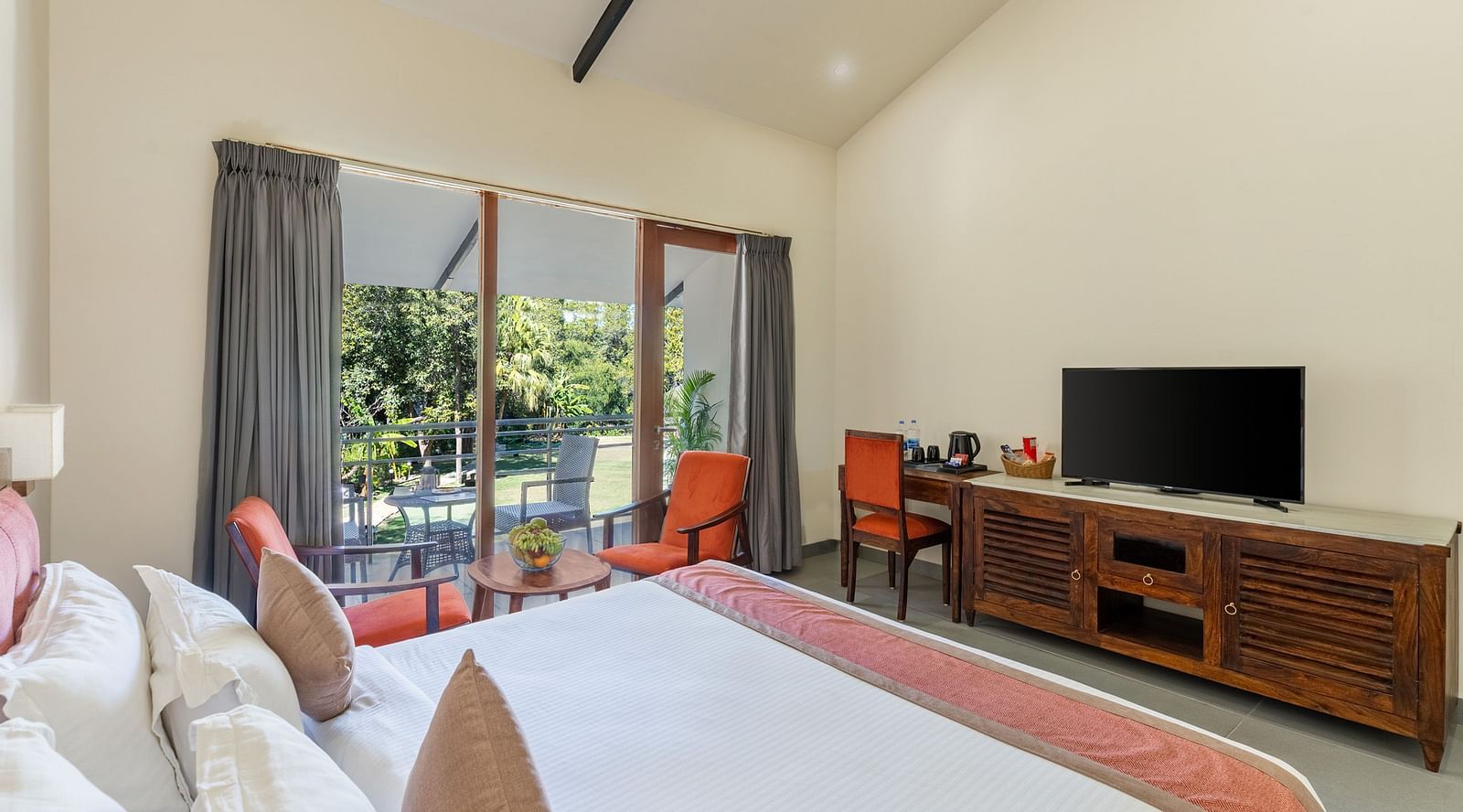 corner view of the luxury cottage room at the aranya vilas featuring a king size bed along with a television screen opposite to it