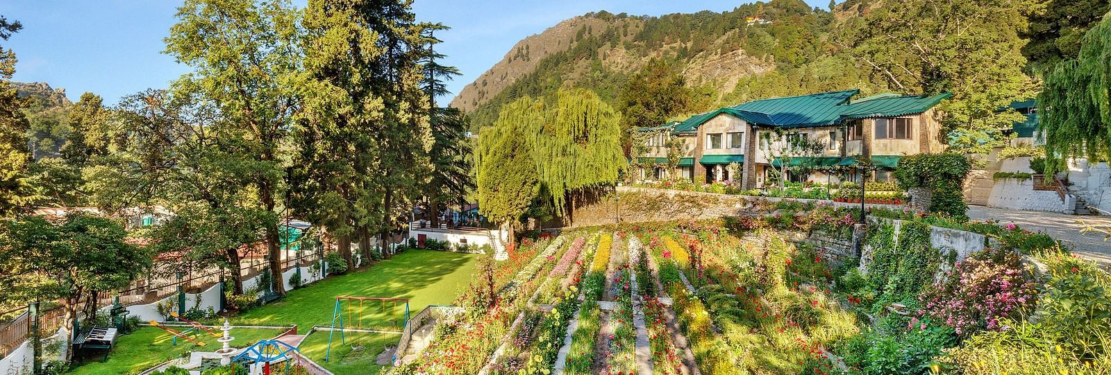   serene lake surrounded by lush green trees and mountains in the background at Shervani Hilltop Nainital 