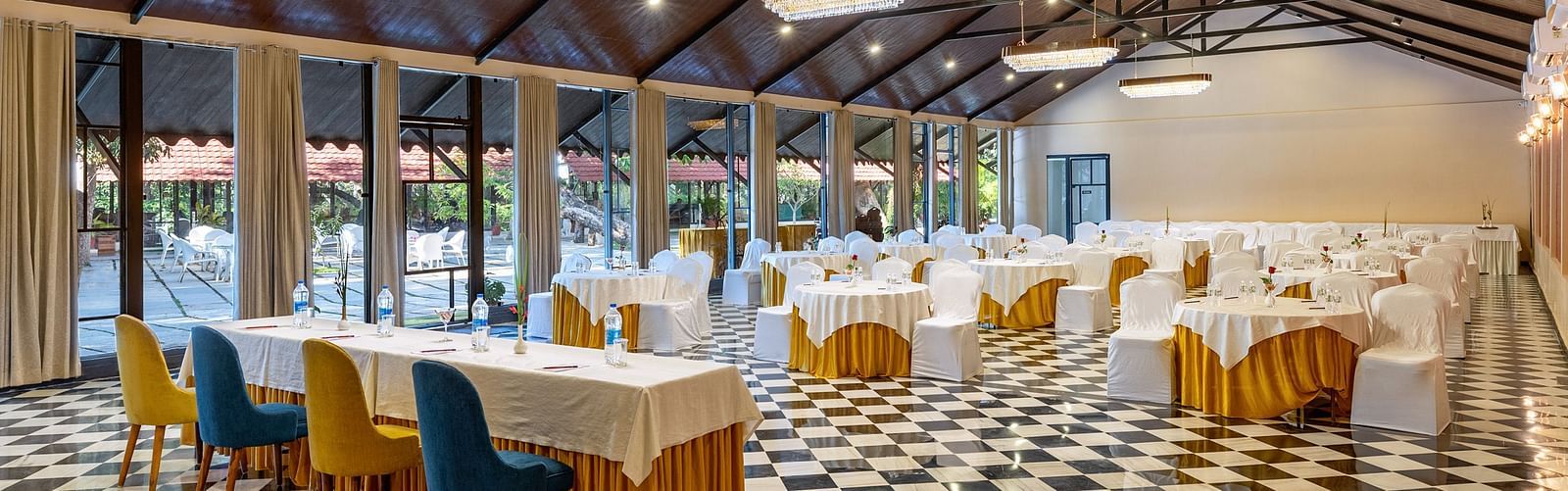 corner view of the banquet hall in udaipur with a high ceiling and properly arranged chairs and tables