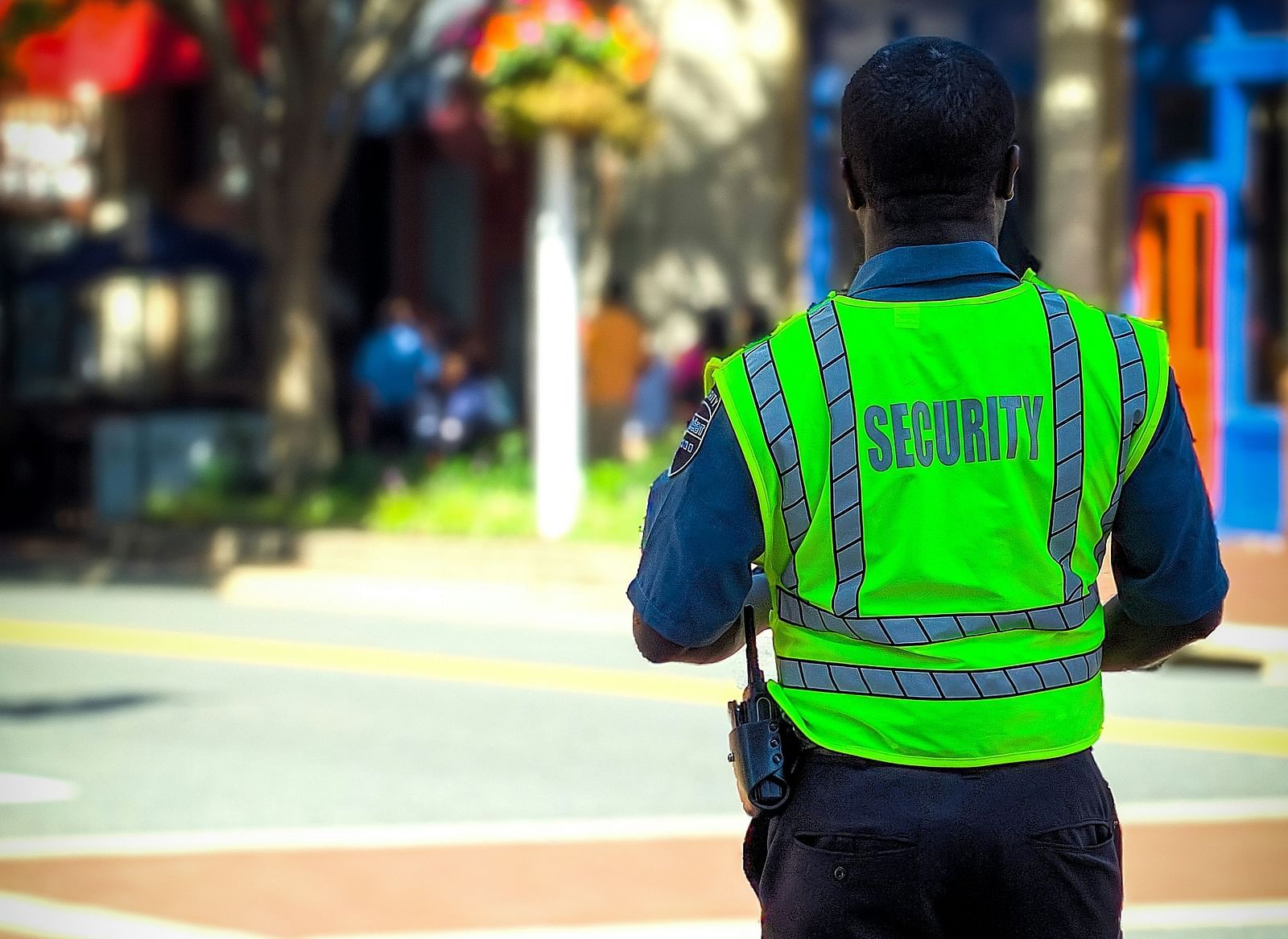 A security wearing a high-visibility vest walking on a paved area.