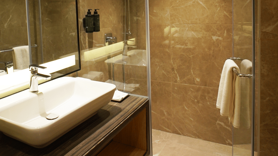 Bathroom sink with mirror and a glass-enclosed shower area - Ramada Encore by Wyndham Gurugram Dwarka Expressway