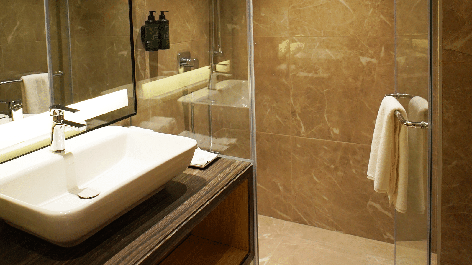 Bathroom sink with mirror and a glass-enclosed shower area - Ramada Encore by Wyndham Gurugram Dwarka Expressway
