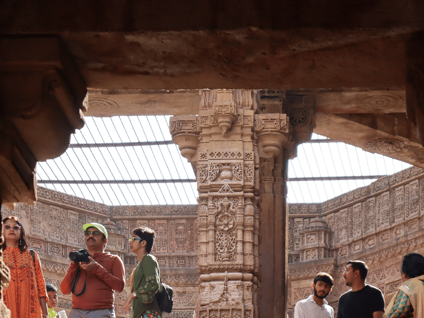 Visitors explore and rest among the grand stone pillars and steps of a historic Indian heritage site.
