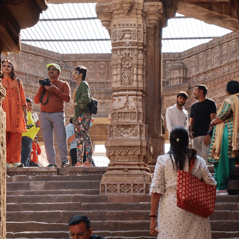 Visitors explore and rest among the grand stone pillars and steps of a historic Indian heritage site.