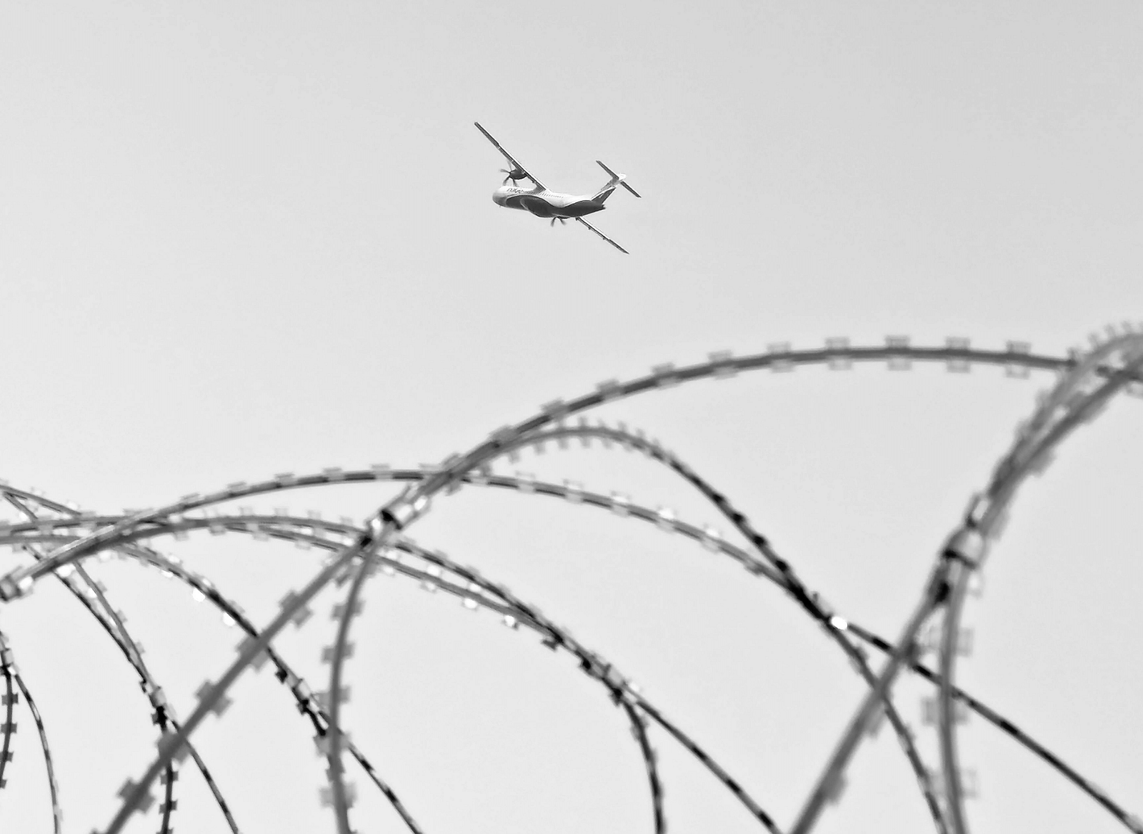 Metal fence with an airplane soaring in the sky above at BluSalzz Residence, Amritsar.