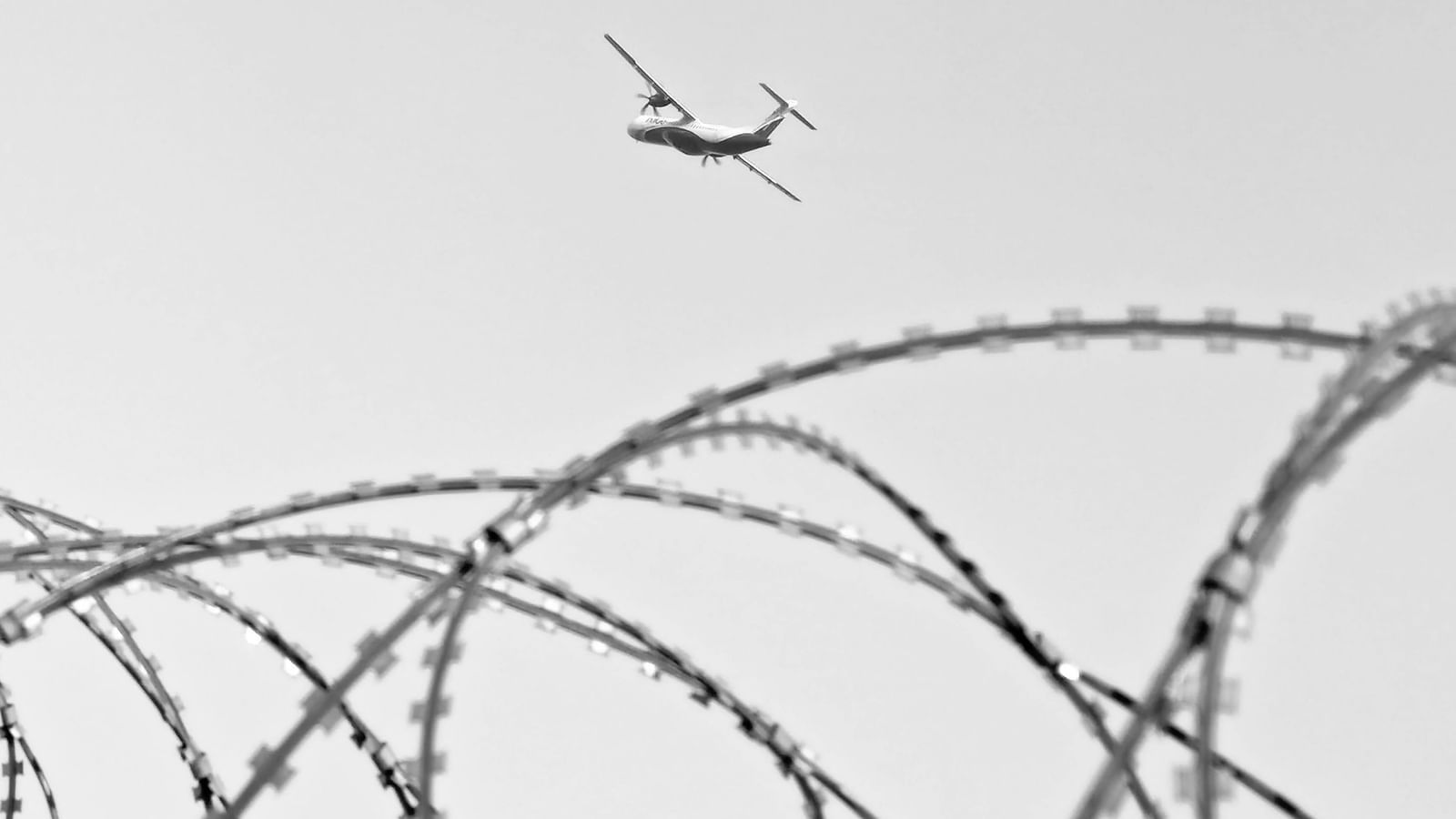 Metal fence with an airplane soaring in the sky above at BluSalzz Residence, Amritsar.