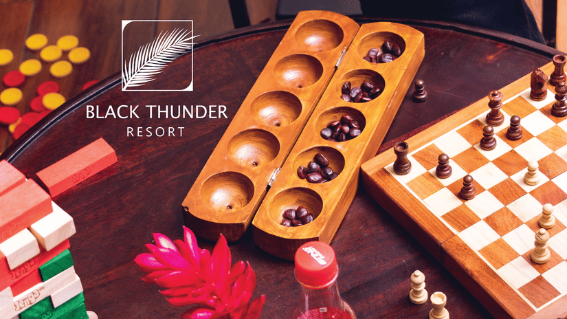 People playing a traditional wooden board game with pieces and tokens, enjoying a fun indoor or outdoor game session - Black Thunder, Coimbatore