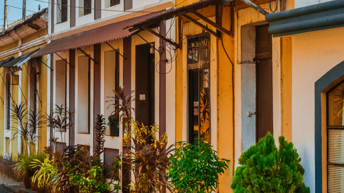 Heritage street in Goa with vibrant colonial-style buildings painted in pastel hues, reflecting Portuguese architectural influence.