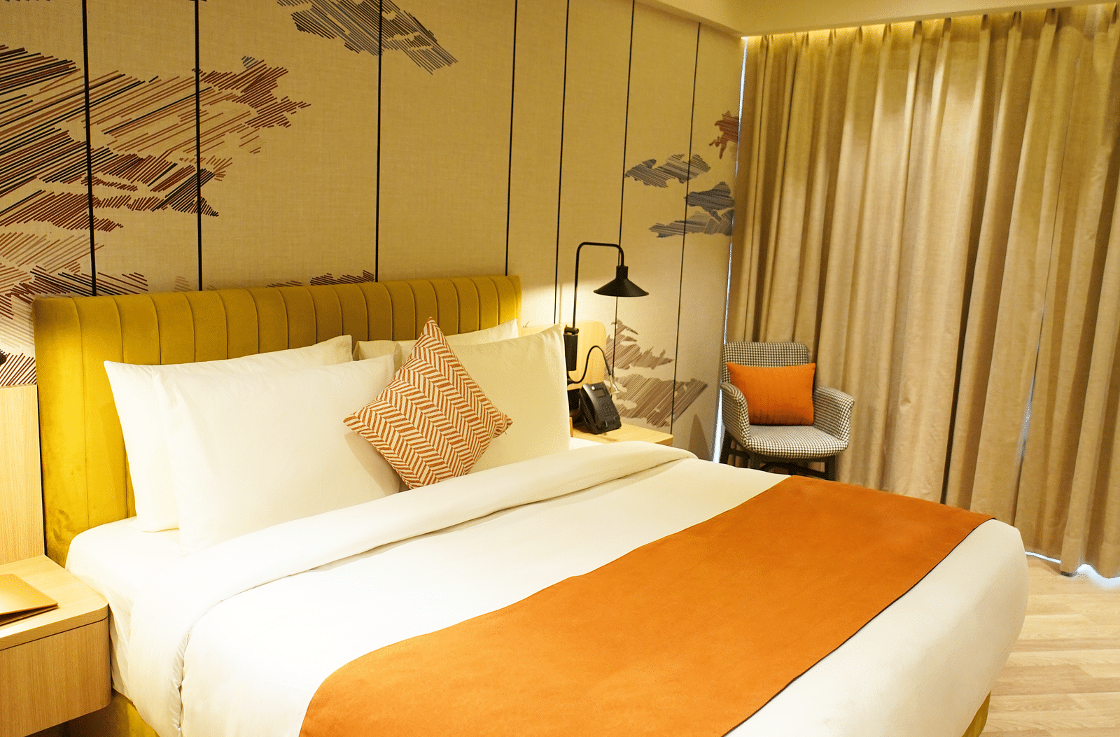 Large bed with cushions and bedside lamps in a stylish room - Ramada Encore by Wyndham Gurugram Dwarka Expressway