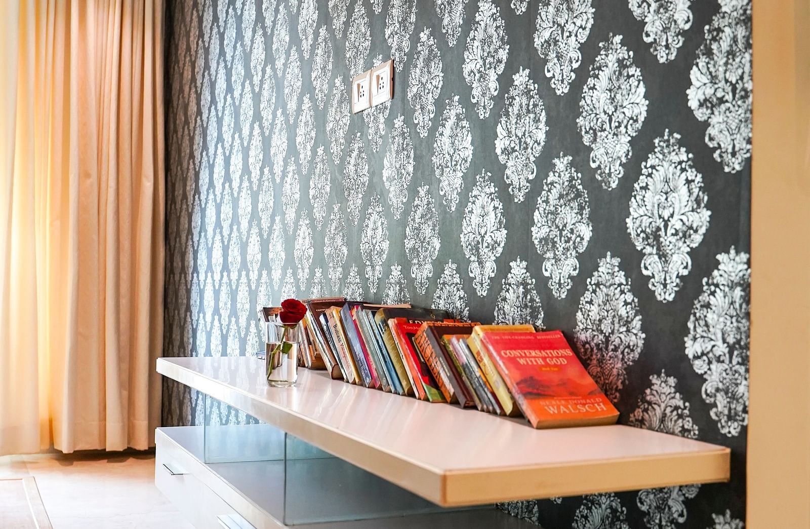 A modern room at BNGV Grandeur Hotel and Banquets featuring a daybed with a patterned wall and a view of a window.