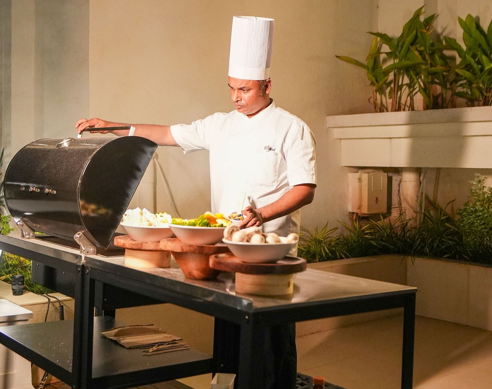 A chef in his attire preparing a counter with various well-plated dishes at the Imperial Goa.