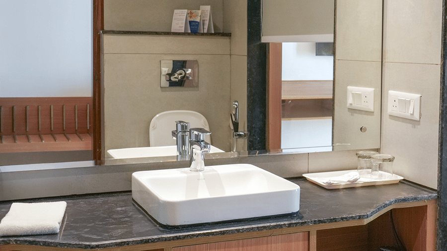 A bathroom area with a vanity counter, a sink, a mirror, and shelves at Ramada by Wyndham Mussoorie Mall Road.