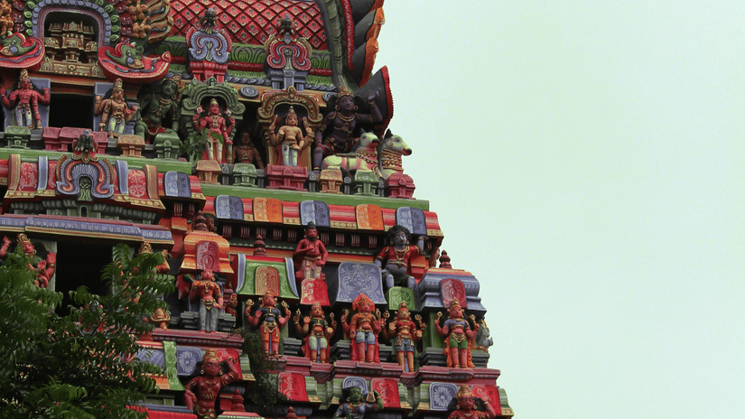 A close-up of the upper section of a large, ancient Hindu temple tower.