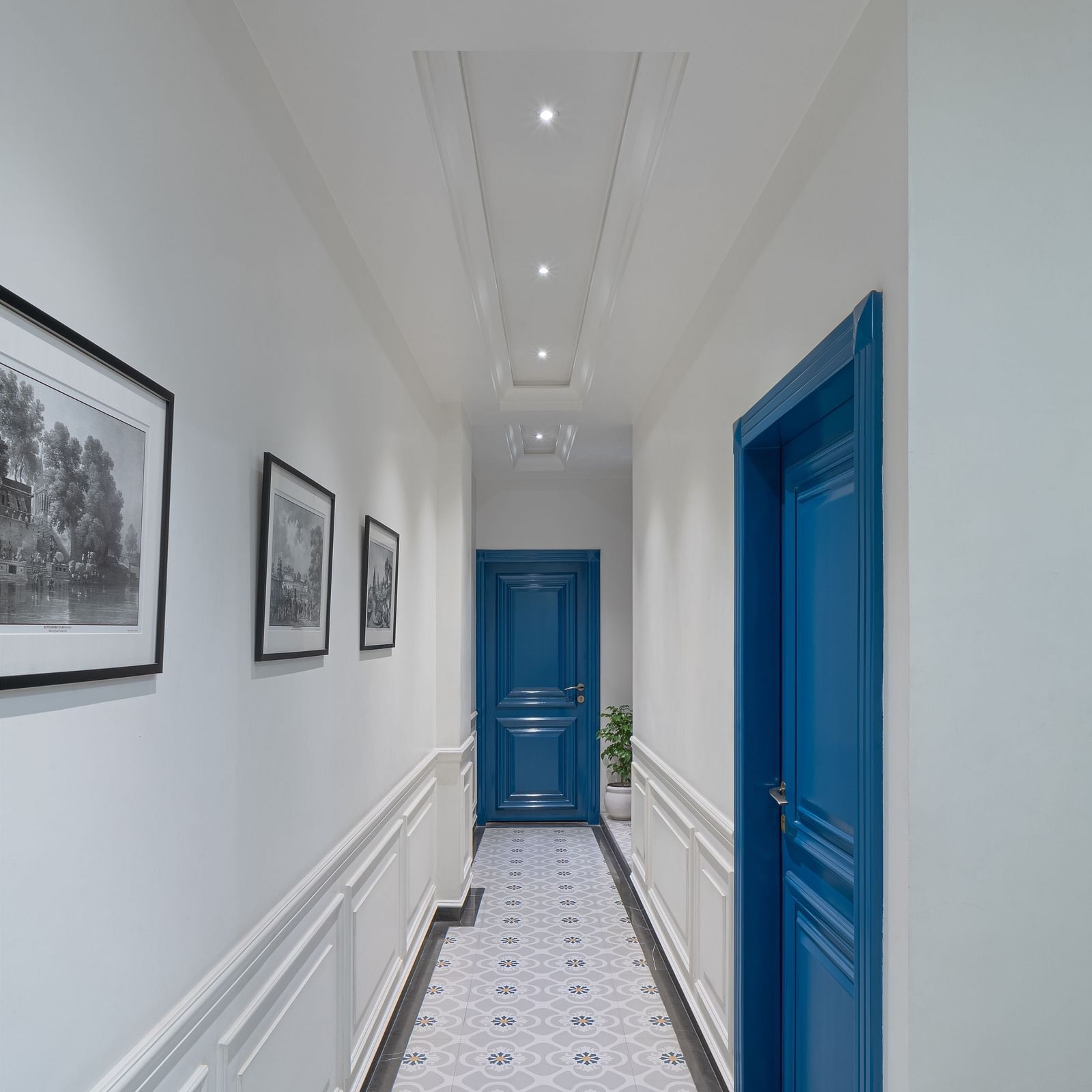 A corridor has a wall-mounted frame on one side and doors on the other side | Hotel Ganga Maiya
