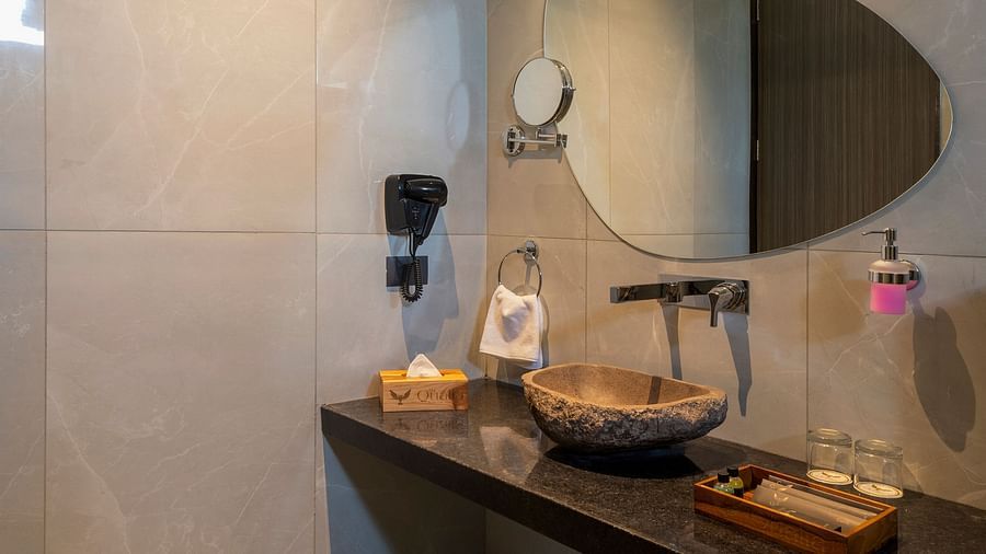 A bathroom of Valley View Room featuring a long vanity with a mirror and soft lighting, emphasising clean lines and neutral tones at The Qualia Resort Club & Brewery, Udaipur.