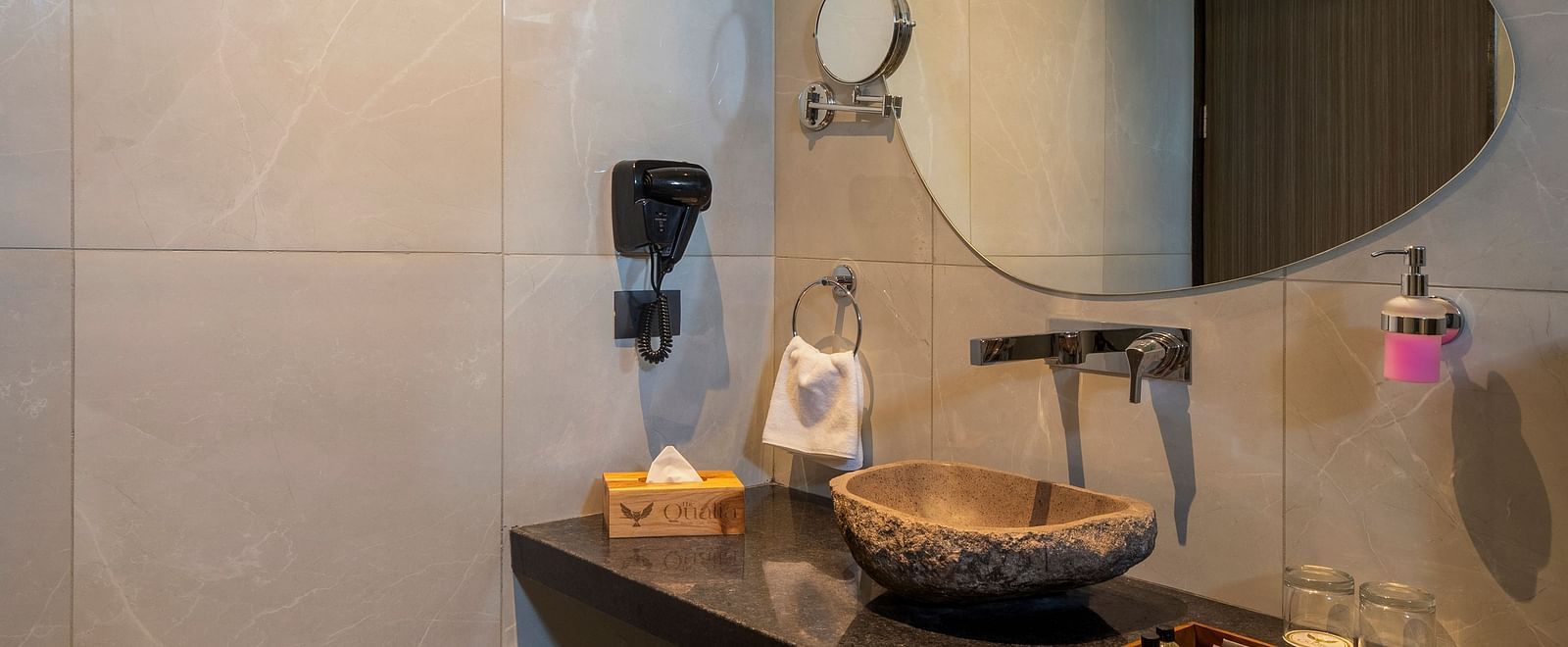 A bathroom of Valley View Room featuring a long vanity with a mirror and soft lighting, emphasising clean lines and neutral tones at The Qualia Resort Club & Brewery, Udaipur.