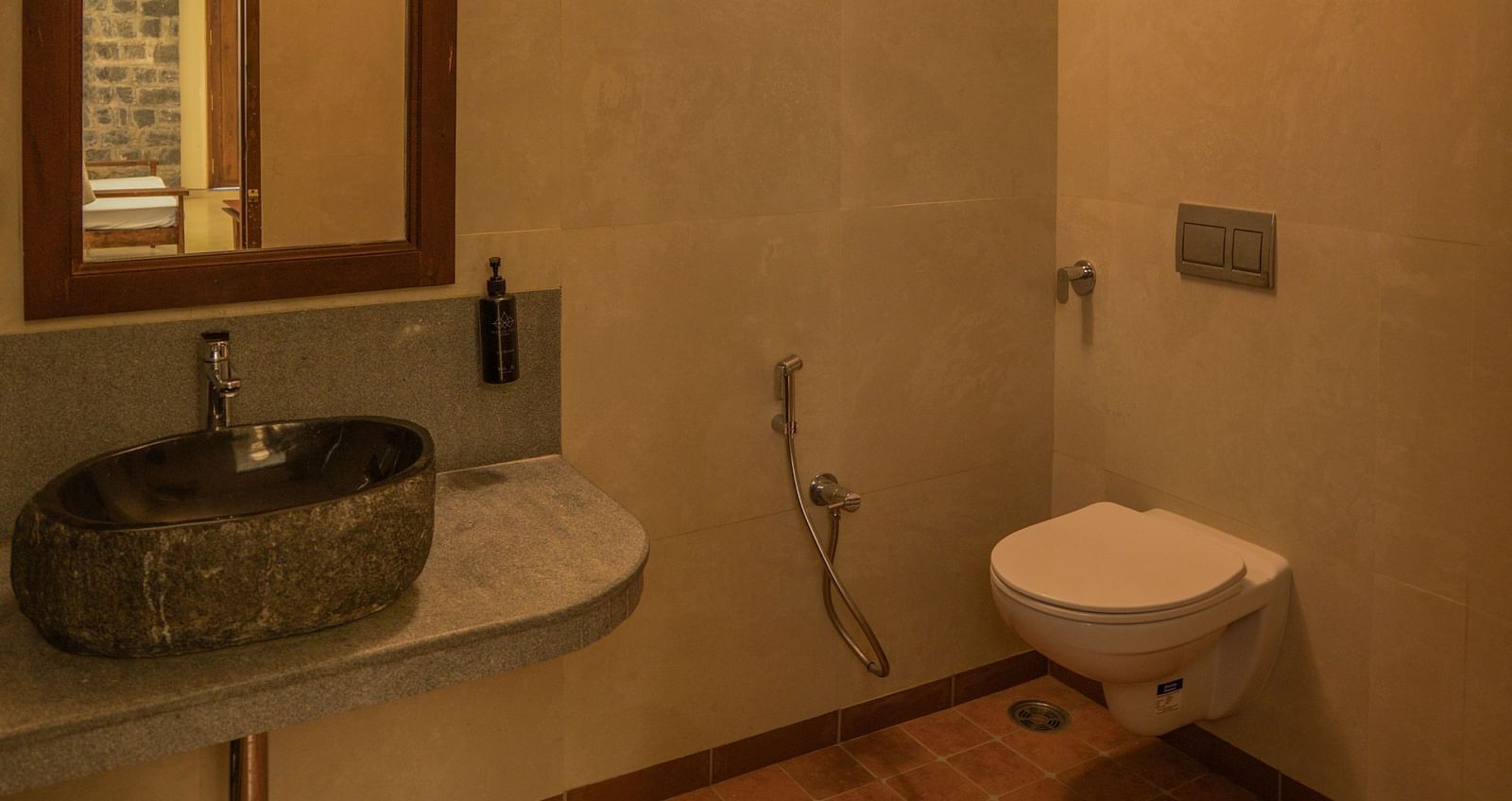 Modern bathroom with a wall-mounted sink, mirror, and a toilet. | Mango Hill, Yercaud