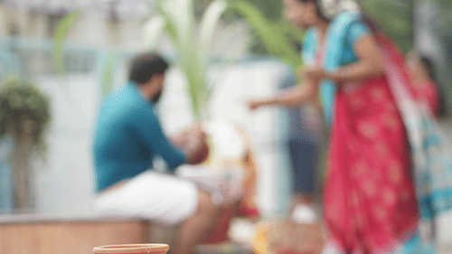 a couple in the background speaking to each other with a pot kept to boil in the foreground