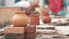 a couple in the background speaking to each other with a pot kept to boil in the foreground