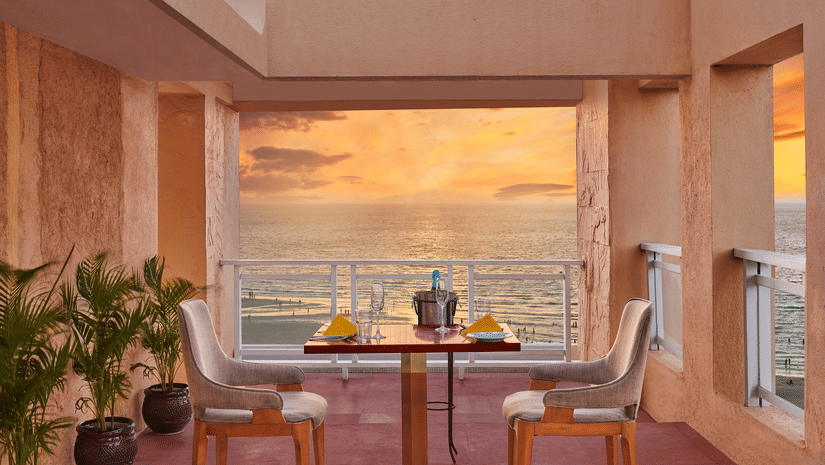 Open terrace dining setup at The Resort, Mumbai overlooking the sea during sunset, with a table for two, warm lighting, and coastal views creating a relaxed ambience.
