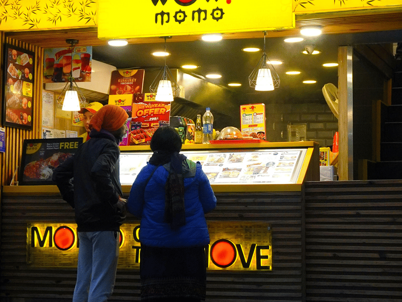A couple of people standing at the ordering counter of Wow Momo, one of the shops at the food court of Quest Mall, Kolkata