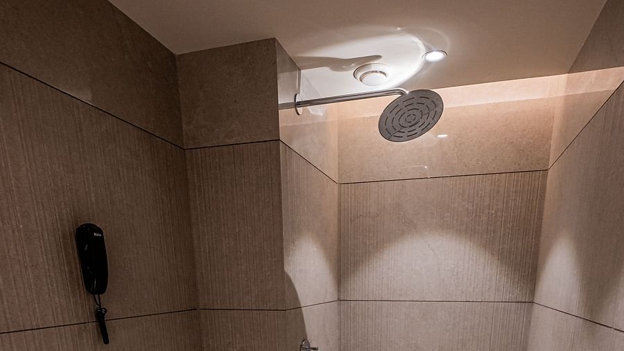 A spacious washroom at Indie Stays Mumbai International Airport, featuring a western toilet and a shower area.