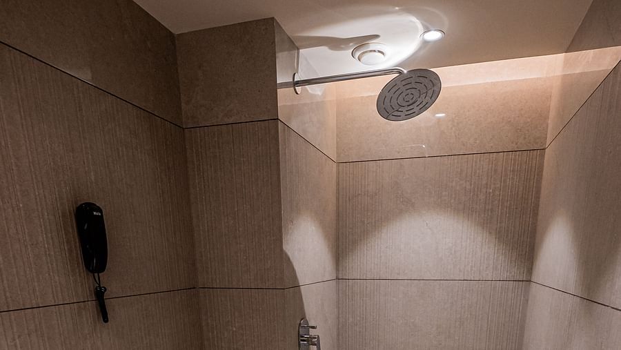 A spacious washroom at Indie Stays Mumbai International Airport, featuring a western toilet and a shower area.