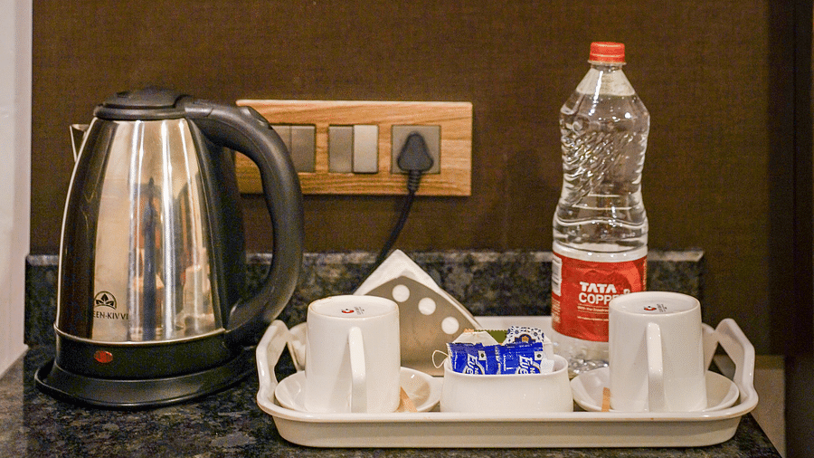 Image of a table with an electric kettle and cups placed on a try at Coorg Jungle Camp Backwater Resort, Kushalnagar.