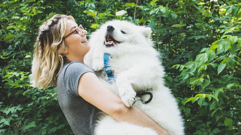 A close up shot of a woman holding a large dog.
