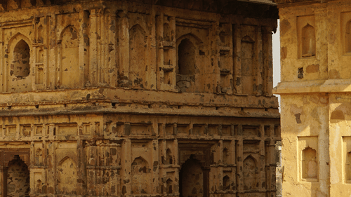 a yellow coloured Temple inside chandragiri fort with a person walking in its shadow