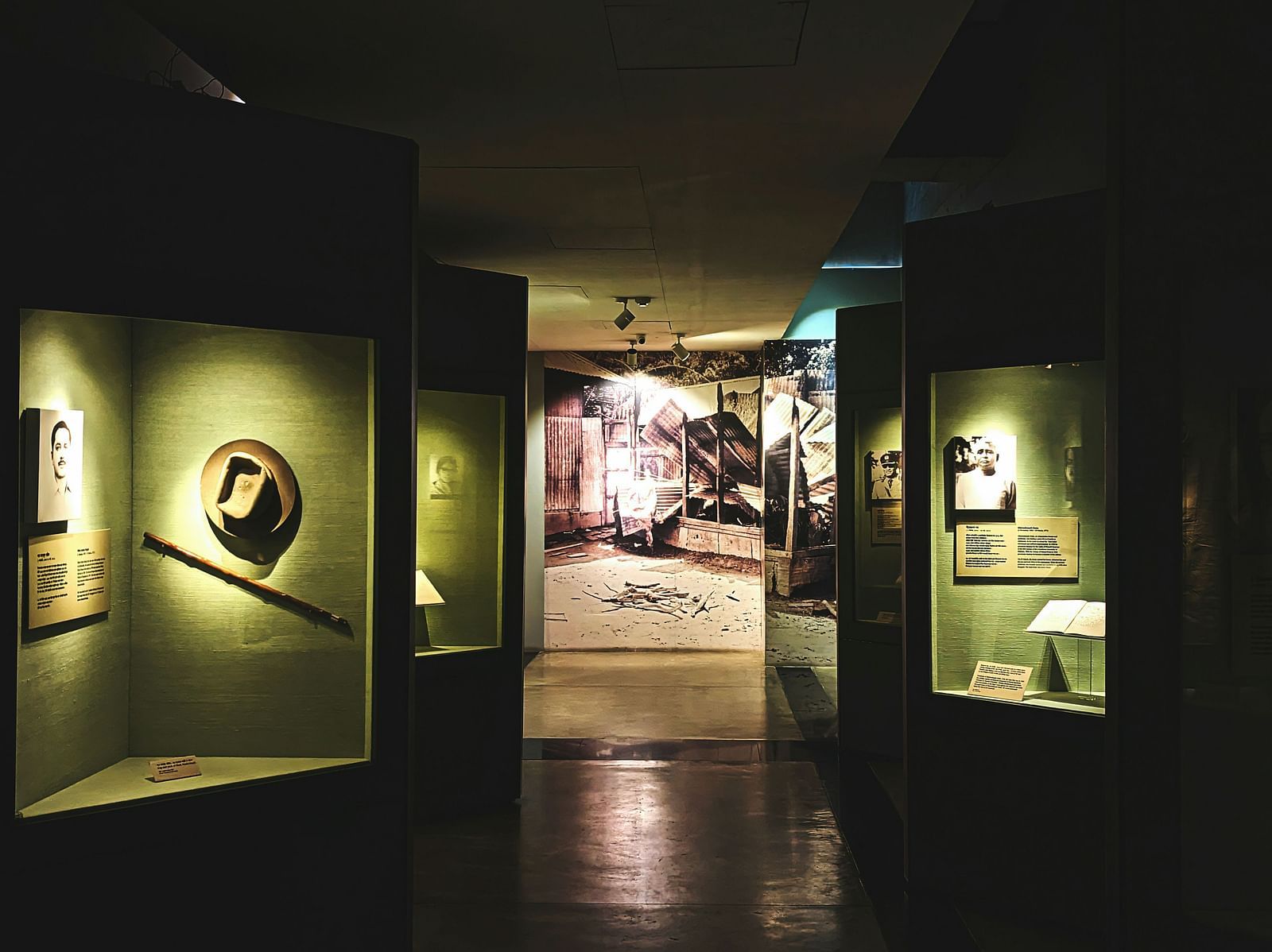 A view of a room inside a museum with art installations on the wall having spotlights on them.