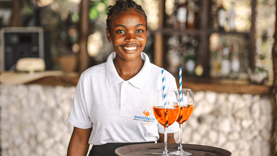 View of a woman holding drinks on a serving tray at Shooting star Boutique Hotel