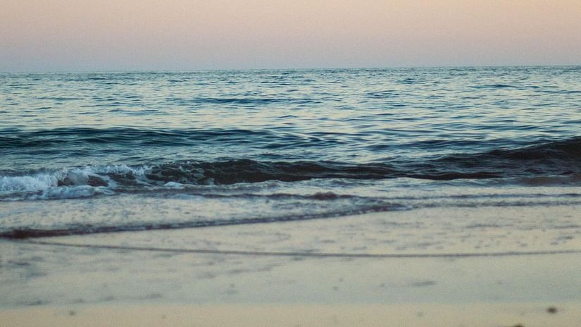 waves of water overlapping on the beach with different hues on the sky after a sunset