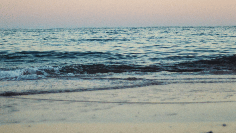 waves of water overlapping on the beach with different hues on the sky after a sunset