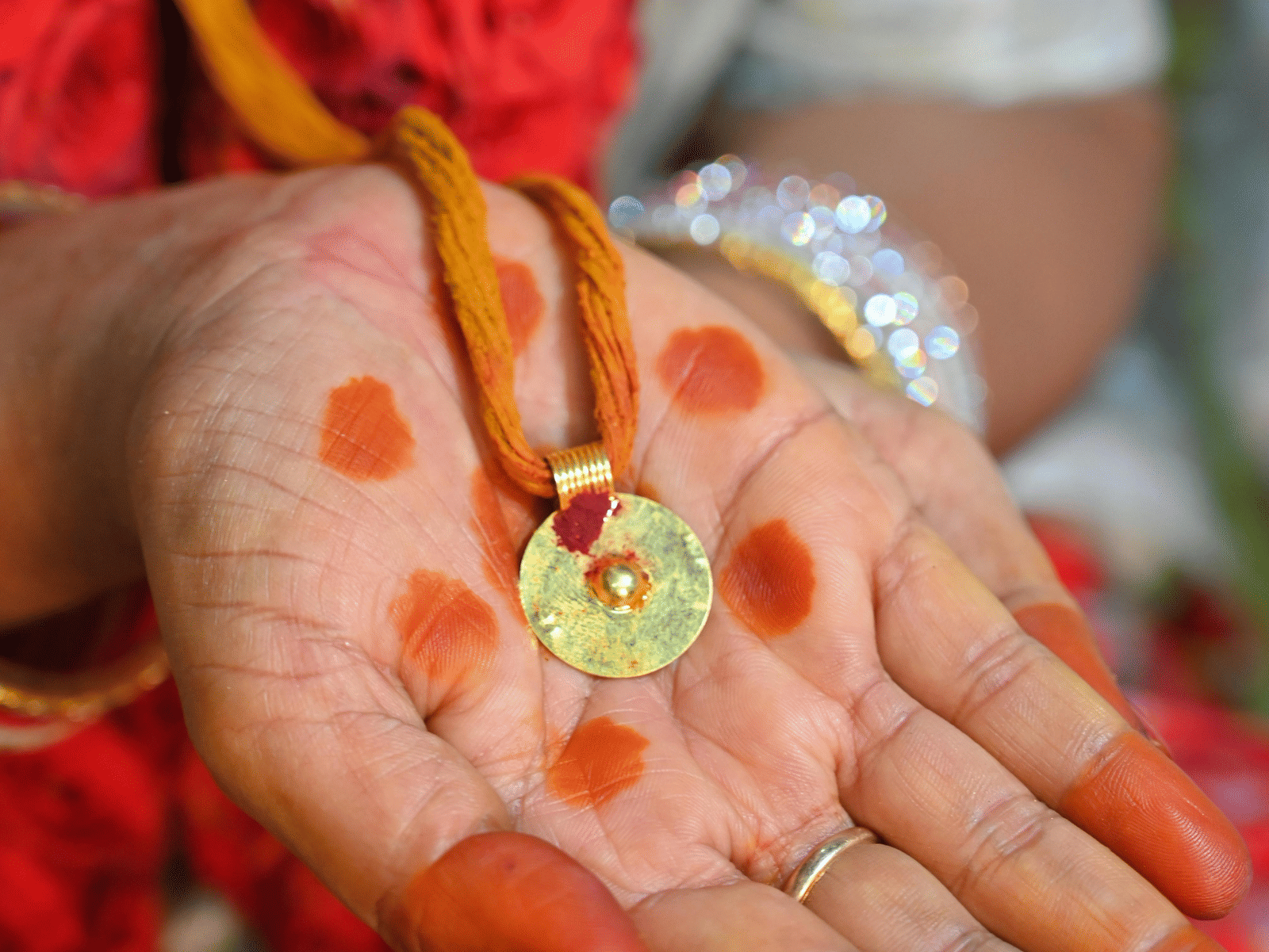 A bride’s hand decorated with kumkum and turmeric during a traditional Indian ceremony.