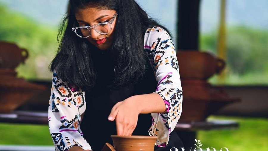 A person working on a pottery wheel, shaping a clay pot.