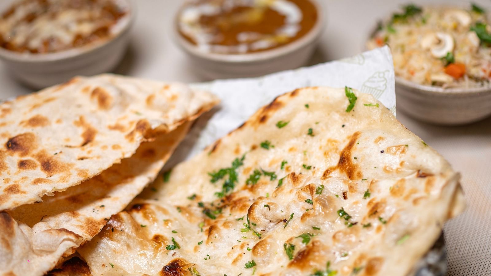 Indian bread served in a basket alongside various gravies in bowls. Meal served at Hotel Moti Palace.
