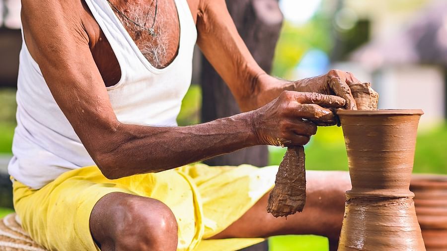 An older man weaving or working with natural materials in an outdoor setting.