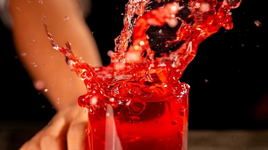An image of a person shaking a glass of beverage which is causing the liquid to spill - The Dukes Retreat, Khandala