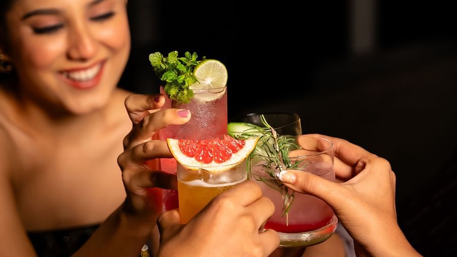 An image of a happy woman clinging her beverage glass with other people around her - The Dukes Retreat, Khandala
