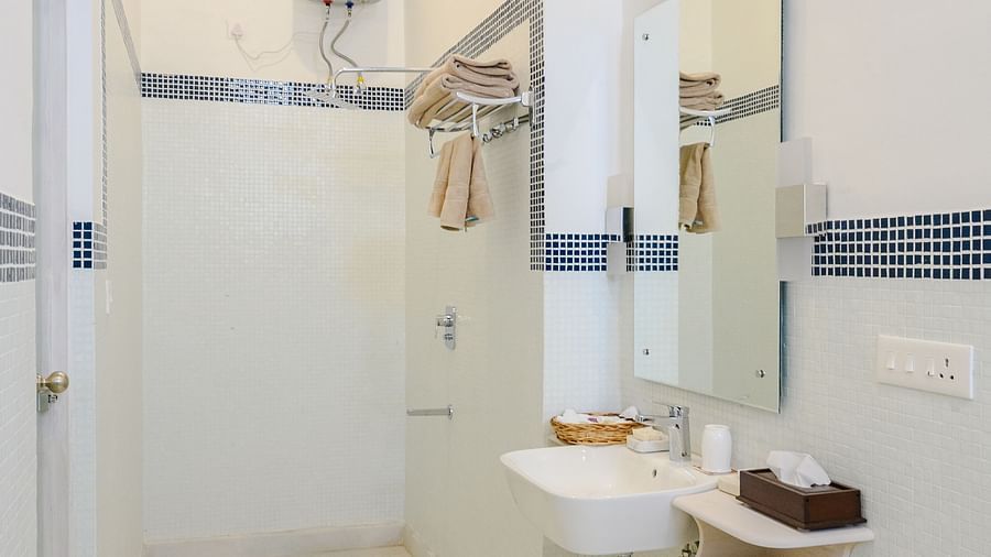 A narrow shot of a bathroom with a toilet, a shower, a geyser and tiled walls on the side. - Tijara Fort-Palace - 19th Century, Alwar