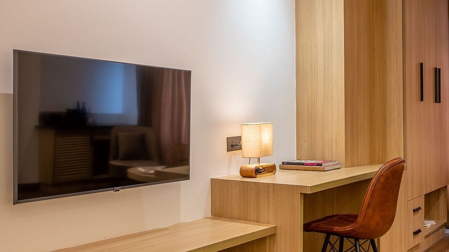 Interior of  a room at Vishranti Hotel, Dehradun featuring a work desk, chair and a TV.